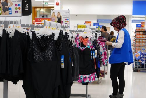 Worker checking price tag for display clothes on sale inside Walmart store