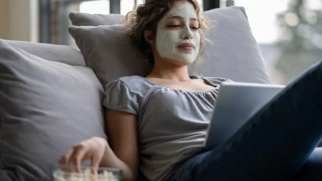 Woman relaxing at home with a facial mask eating pop corn while a picture id1242508945