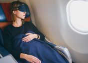 woman sleeping on a plane with blanket and eye mask