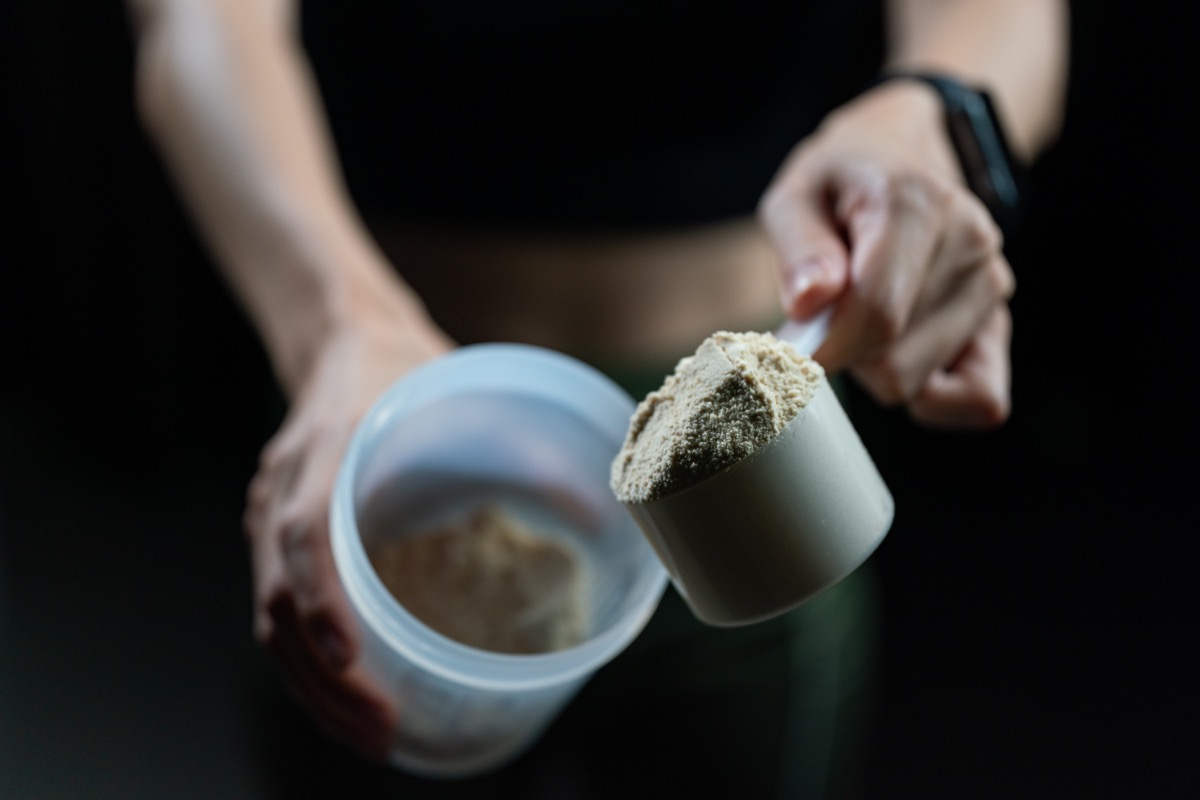 Closeup woman's hand scooping whey protein