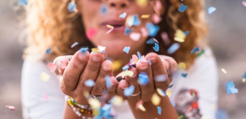 woman blowing confetti and sending happy birthday wishes