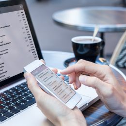 A close up of a person checking their email on a laptop a smartphone