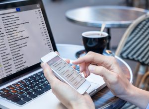 A close up of a person checking their email on a laptop a smartphone