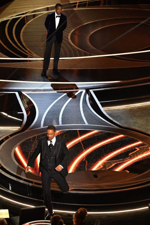 Chris Rock on stage and Will Smith leaving the stage at the 2022 Oscars