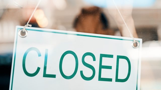 A closed sign hanging the the front door of a restaurant or store