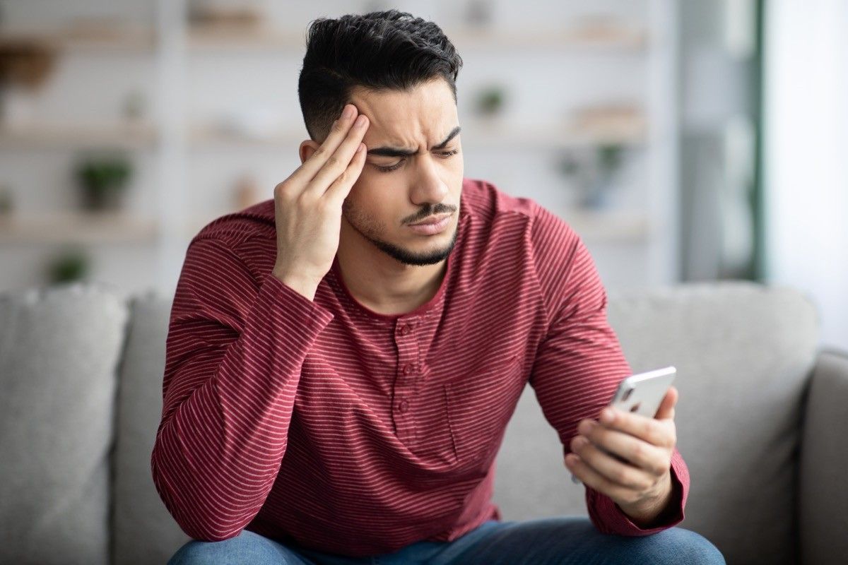 guy sitting on sofa at home using smartphone