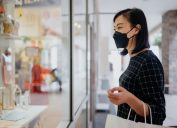 woman wearing protective face mask and looking at the store display of a gift shop
