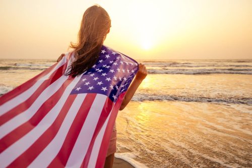 woman looking at ocean with a flag on the 4th of july