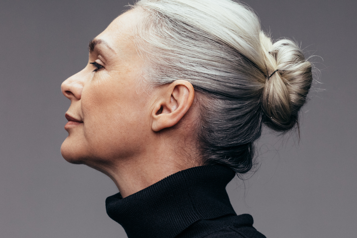 Side view of a senior woman with gray hair in a bun, wearing a black turtleneck