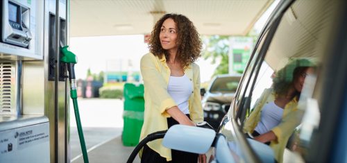 femeie zâmbind la pompa de benzină