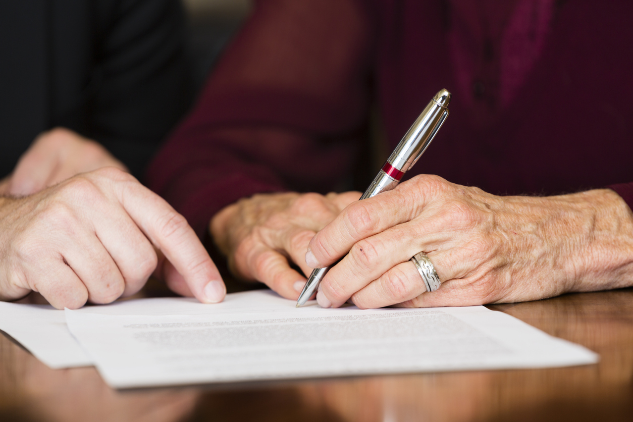 Un vârstnic semnează un document.
