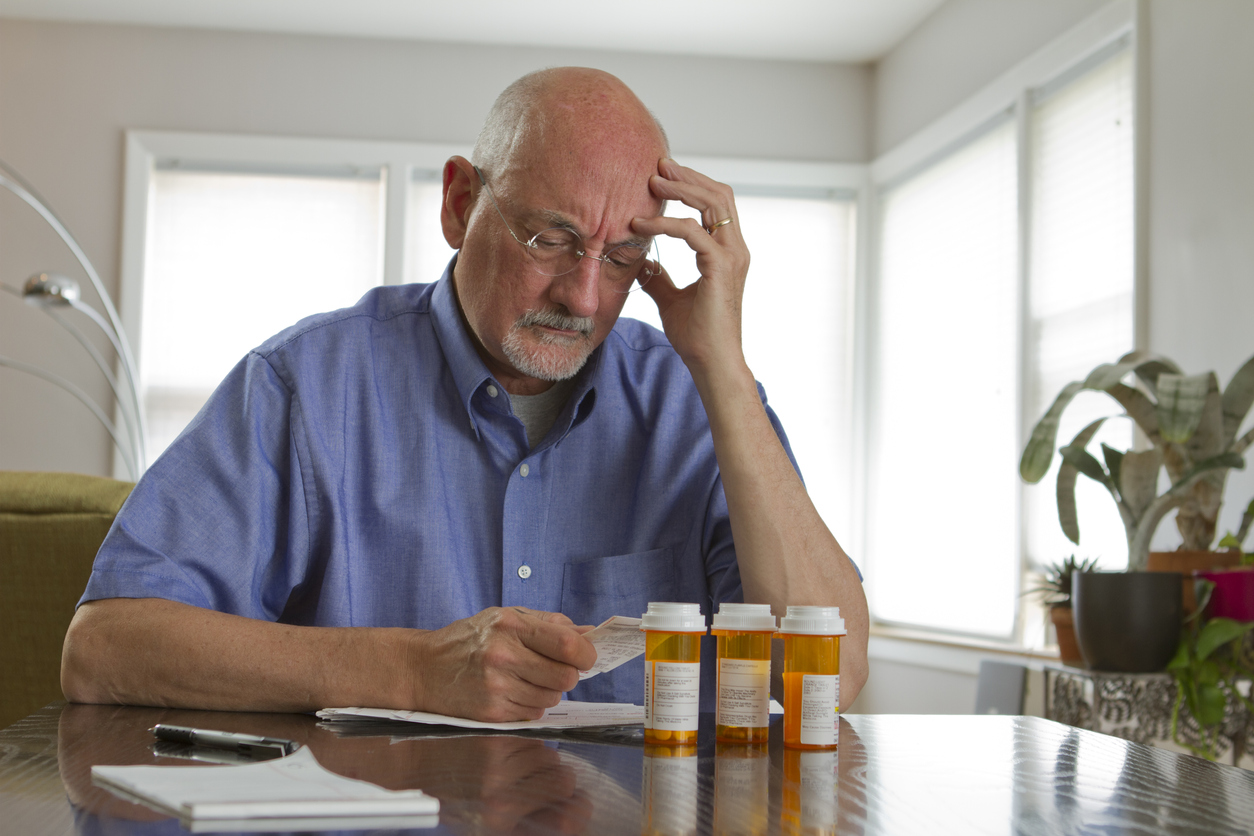Confused older man looking at prescription bottles