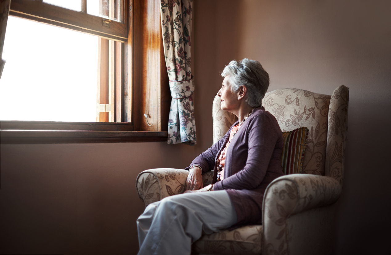 A senior woman sitting alone in her living room.