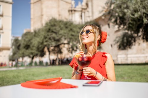 Tânără în roșu savurând sangria, băutură alcoolică tradițională spaniolă, stând în aer liber în centrul vechi al orașului Valencia