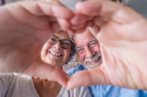 mature man and woman creating a heart out of their hands