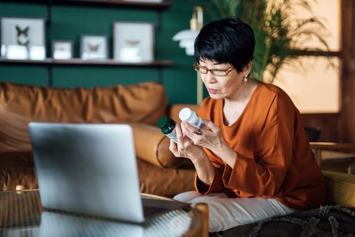 Senior woman having a virtual appointment with doctor online, consulting her prescription and choice of medication on laptop at home. Telemedicine, elderly and healthcare concept