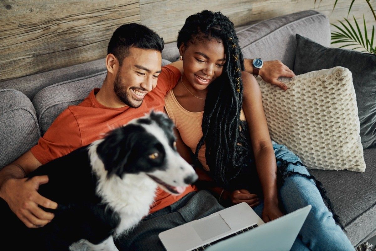 man and woman with dog on couch