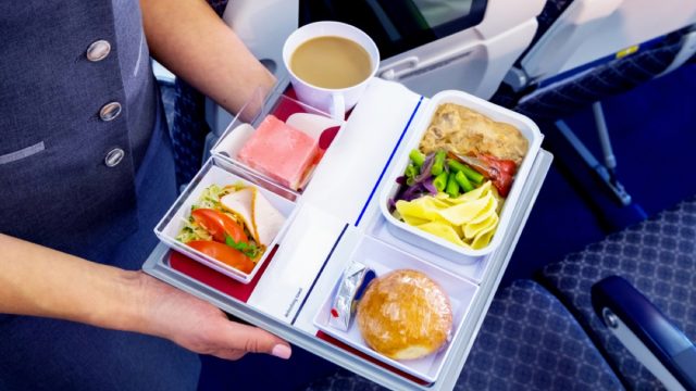 tray of airplane food served by flight attendant
