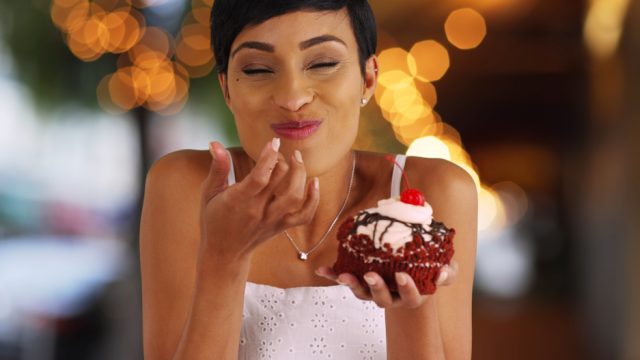 Smiling,Black,Female,Eating,Fancy,Cupcake,In,Outdoor,Setting,With