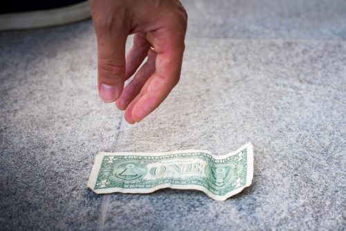 Întinde mâna în jos pentru a ridica o bancnotă de un dolar