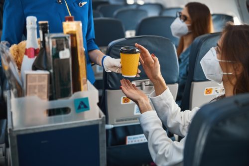 flight attendant serving drink on plane