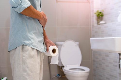 Person Clutching Toilet Paper Roll and Stomach`