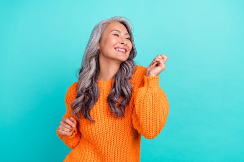 Woman in Orange Sweater with Long Wavy Gray Hair