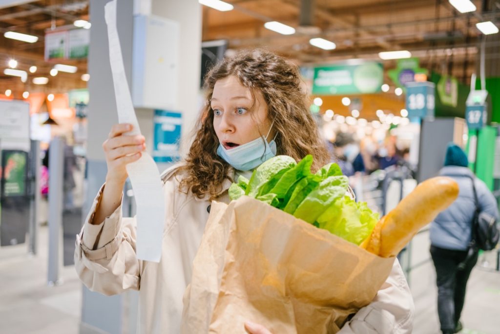 woman looking surprised at grocery receipt