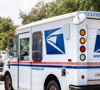 Small USPS van truck delivering packages in Florida, on street road driving