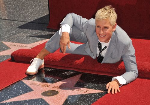Ellen DeGeneres posing with her star on the Hollywood Walk of Fame.