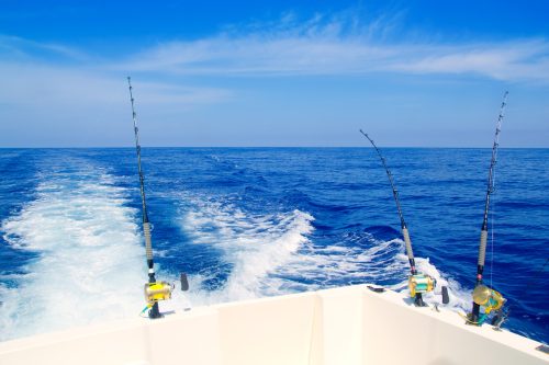 A boat in deep blue waters with three fishing poles