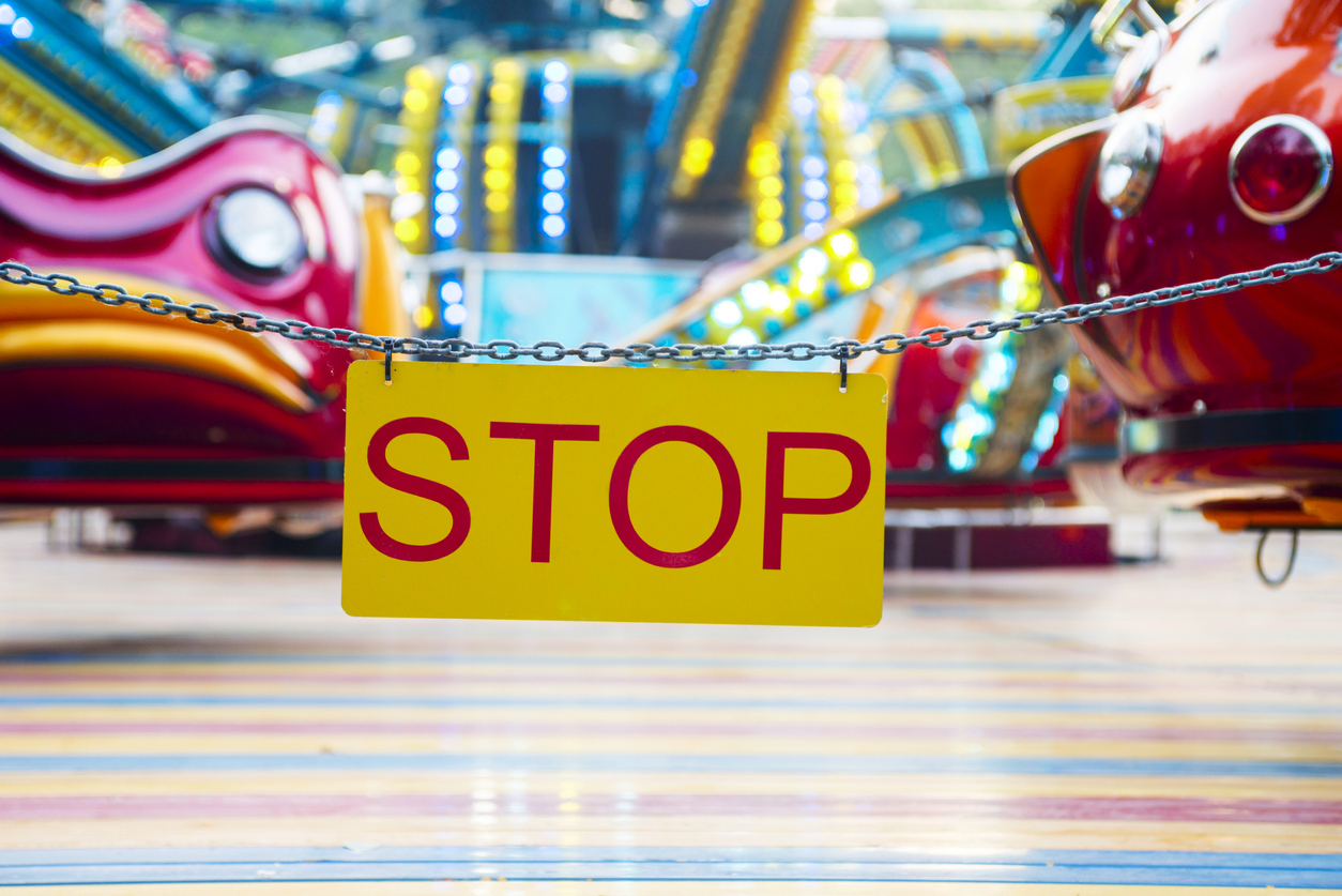 A "STOP" sign hanging in front of a closed amusement park ride