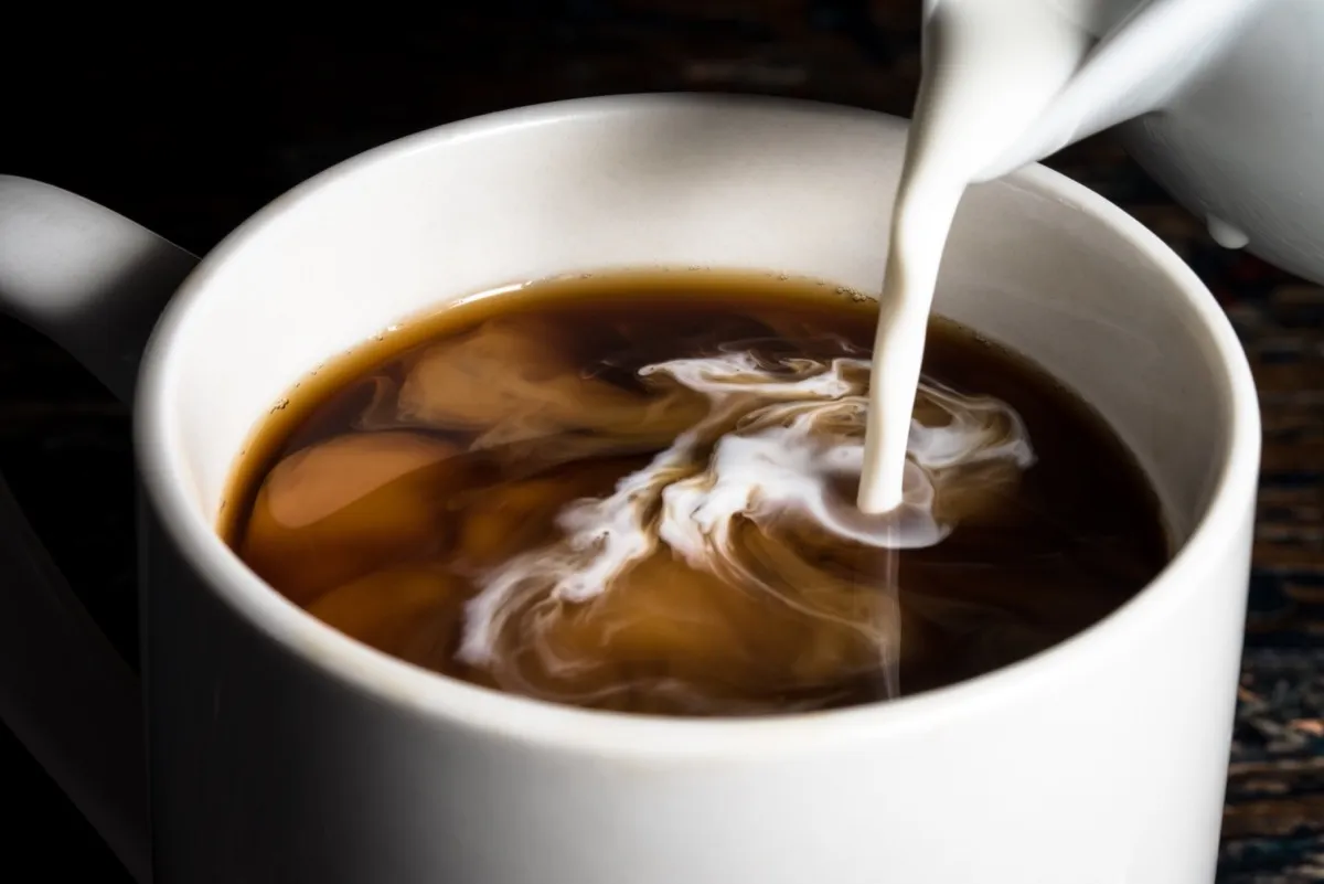 Pouring Creamer into a Cup of Coffee