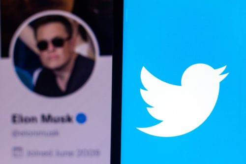 the Twitter logo seen displayed on a smartphone with the Elon Musk's official Twitter profile