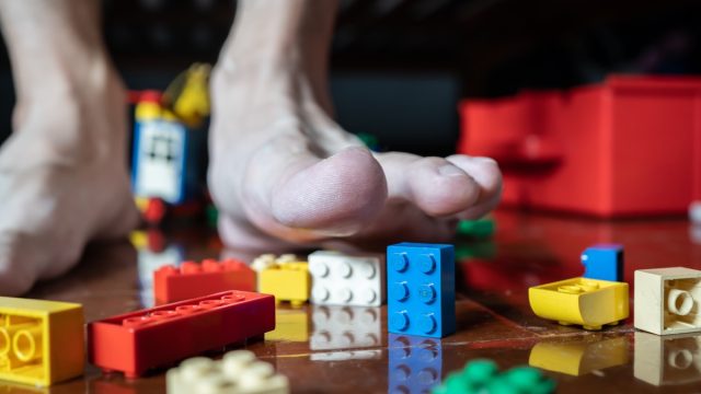 A man avoids to stepping on Lego bricks on the floor.