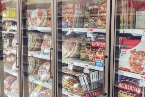 Moorhead, Minnesota, United States - December 7, 2015: Freezer full of pizza in local supermarket, seen through the glass.