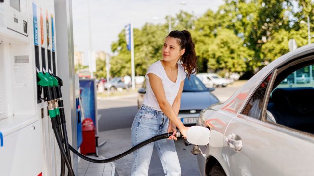 Upset woman refueling the gas tank at fuel pump