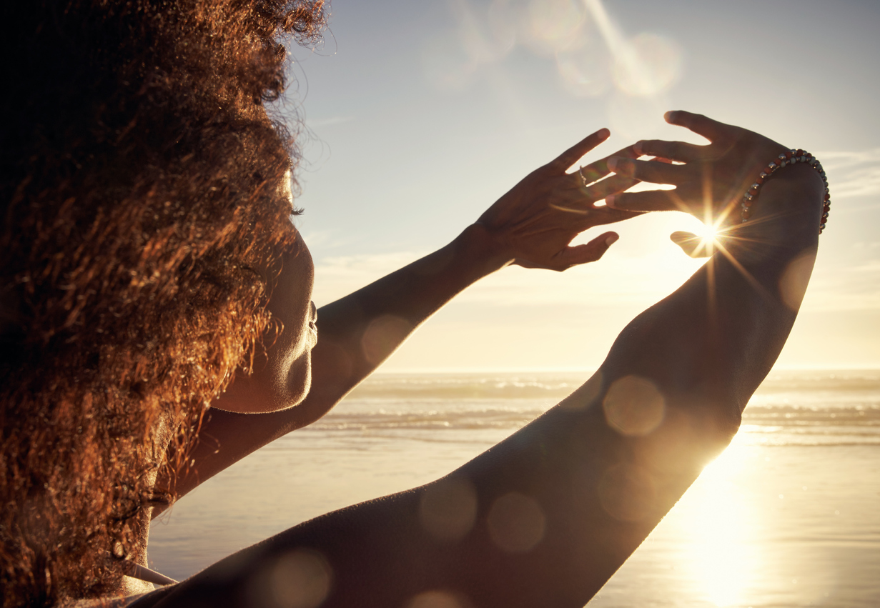 Mujer bloqueando la luz del sol con las manos en la playa.