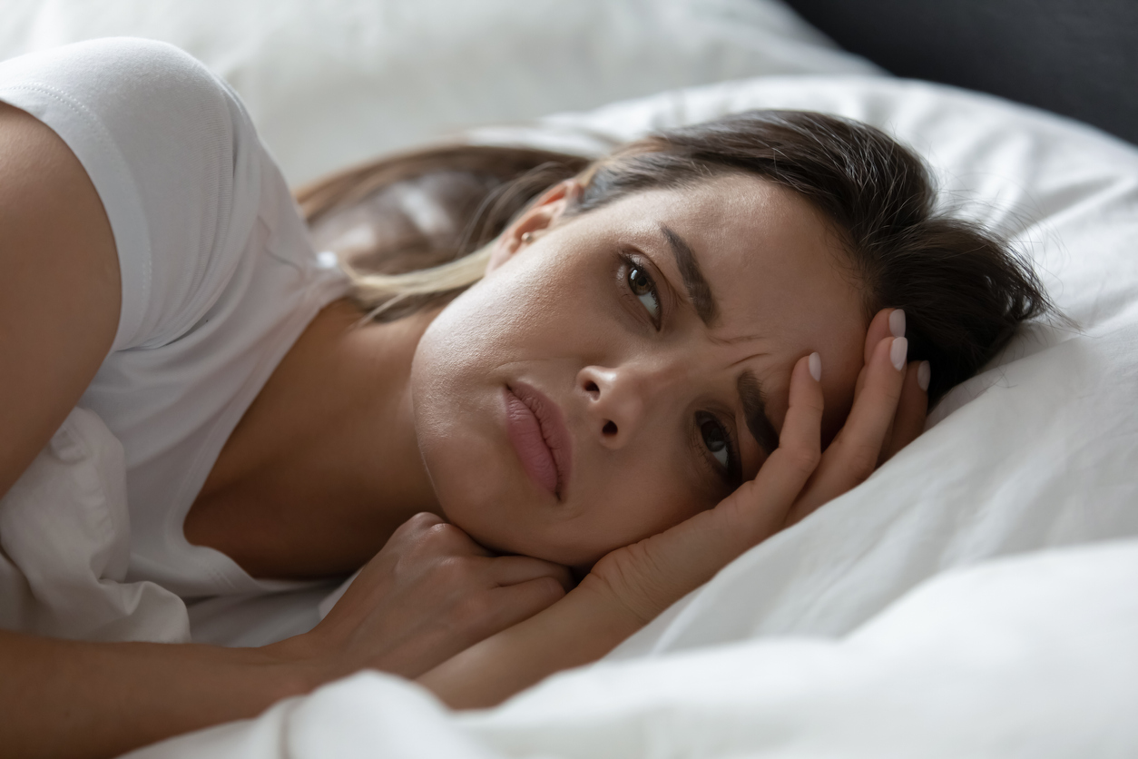 Woman lying in bed, stressed out.
