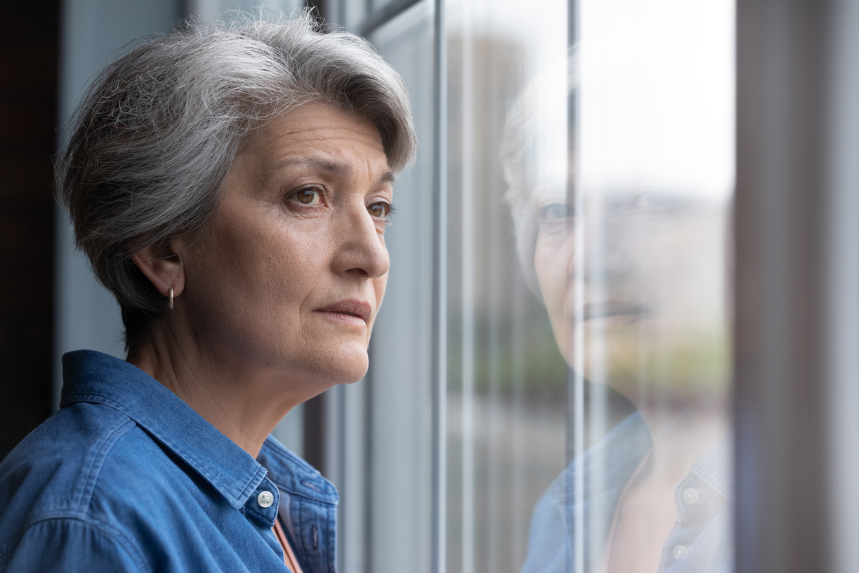 Sad elderly woman looking out the window.