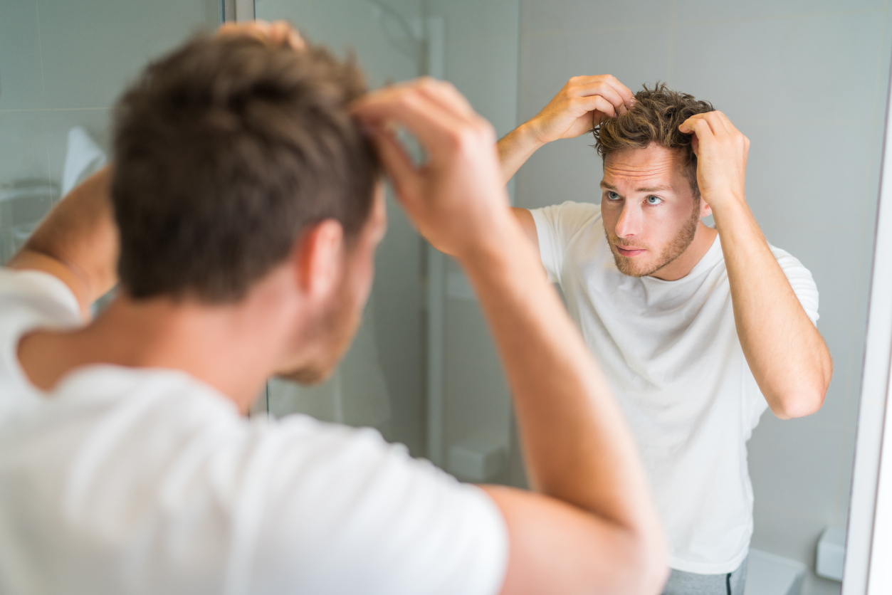 Man looking at his hair in the mirror.
