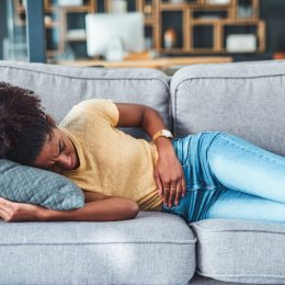 Woman lying on a couch with stomach discomfort.