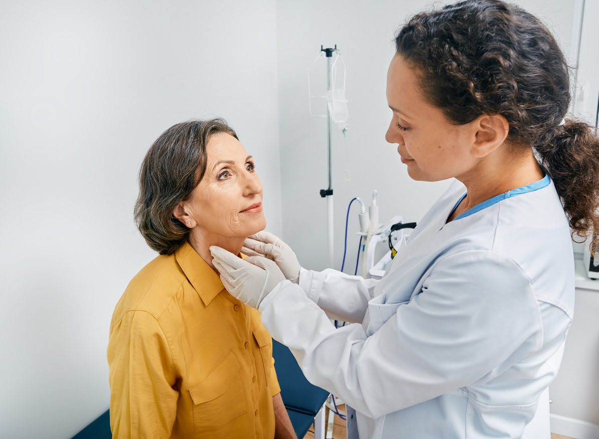 Doctor checking the thyroid of a patient.