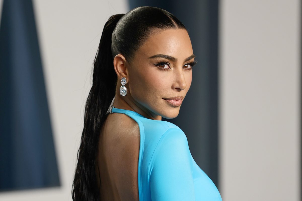 Kim Kardashian at the 2022 Vanity Fair Oscar Party, wearing a blue backless dress and looking over her shoulder.