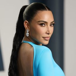 Kim Kardashian at the 2022 Vanity Fair Oscar Party, wearing a blue backless dress and looking over her shoulder.