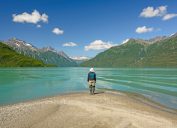A hiker standing on the shore of a lake in Lake Clark National Park