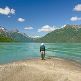 A hiker standing on the shore of a lake in Lake Clark National Park