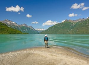A hiker standing on the shore of a lake in Lake Clark National Park
