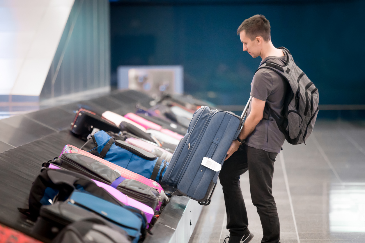 A young man grabbing his checked luggage from a carousel