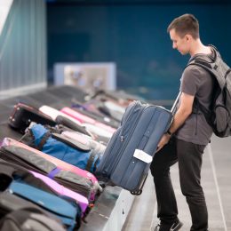 A young man grabbing his checked luggage from a carousel